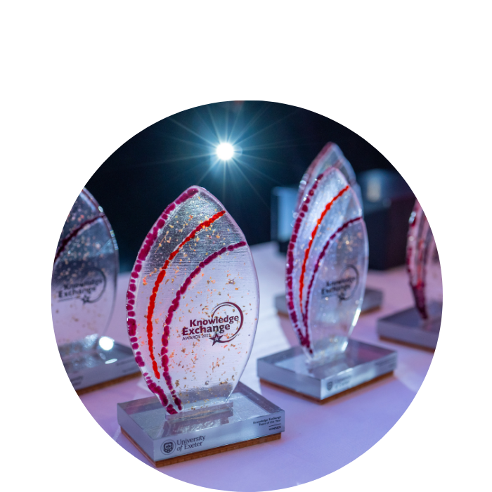Glass knowledge exchange award trophies on a table with a white table cloth